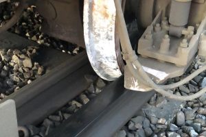 A photo of a train wheel slipped between one line of track and the third rail
