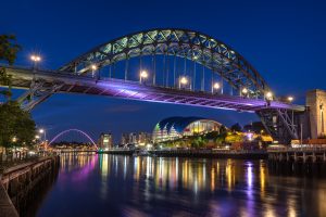 A stock image of the Tyne Bridge at night, illuminated in purple