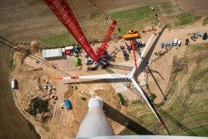 An aerial shot of partially assembled wind turbine blades on the ground with associated construction activity