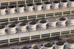 An aerial photograph taken from a helicopter of cooling towers at a large combined cycle gas turbine (CCGT) power station in the UK. Many round steam condenser vents used to cool waste water.